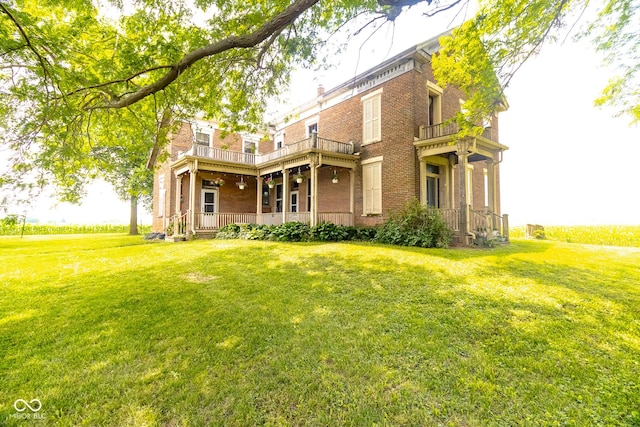 9665 N County Rd 250 E, Frankfort, IN 46041 - rear view of house featuring a balcony, brick siding, a porch, and a lawn