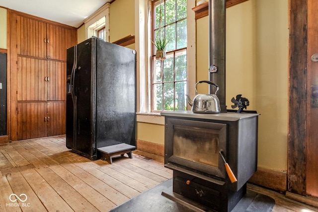 9665 N County Rd 250 E, Frankfort, IN 46041 - kitchen with black refrigerator with ice dispenser, plenty of natural light, a wood stove, and light wood-style flooring