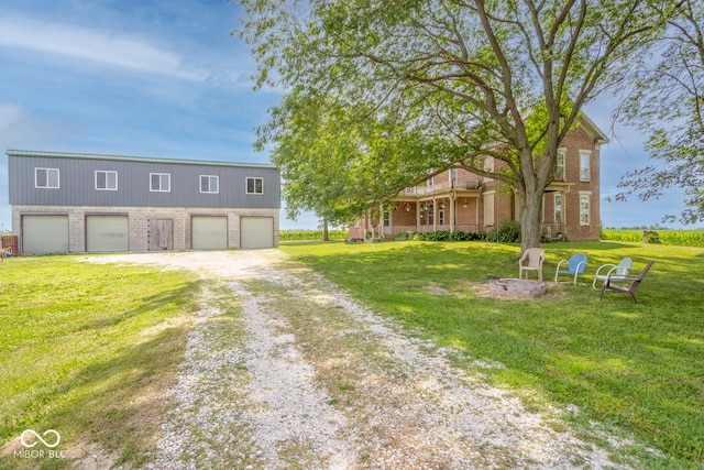 9665 N County Rd 250 E, Frankfort, IN 46041 - view of front facade featuring brick siding, driveway, a front yard, a garage, and a fire pit
