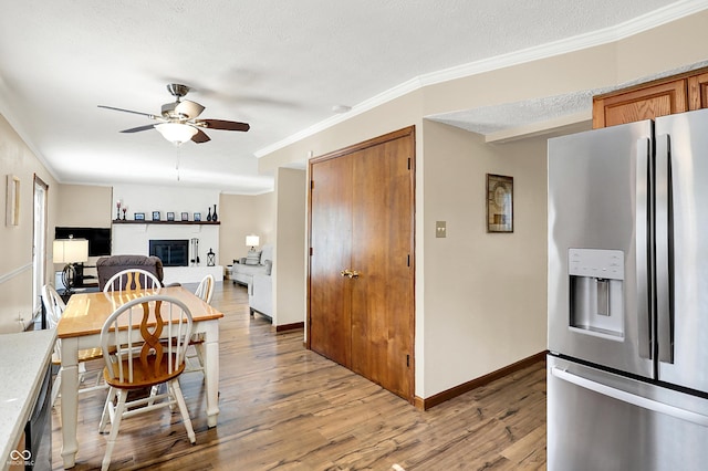 8413 Slippery Elm Ct, Indianapolis, IN 46227 - dining room with ceiling fan, light wood-type flooring, crown molding, a glass covered fireplace, and a textured ceiling