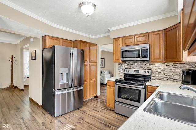 8413 Slippery Elm Ct, Indianapolis, IN 46227 - kitchen with stainless steel appliances, light countertops, light wood finished floors, backsplash, and crown molding