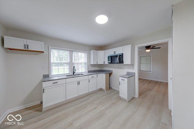 3725 Carson Ave, Indianapolis, IN 46227 - kitchen featuring stainless steel microwave, light wood finished floors, white cabinets, ceiling fan, and light stone counters