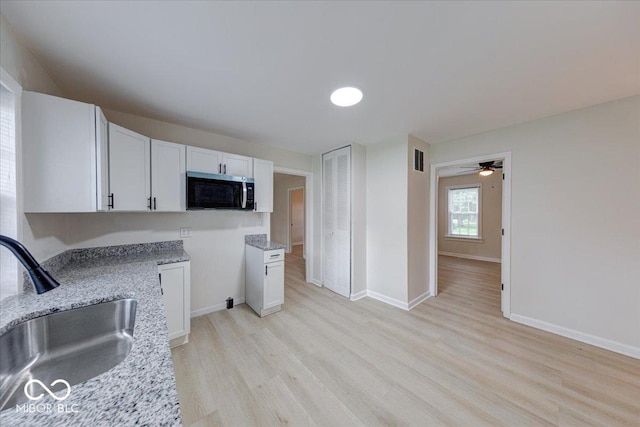 3725 Carson Ave, Indianapolis, IN 46227 - kitchen featuring stainless steel microwave, light wood-style floors, light stone counters, white cabinetry, and ceiling fan