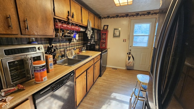 6714 Granner Ct, Indianapolis, IN 46221 - kitchen with black appliances, light countertops, brown cabinetry, light wood-style floors, and a textured ceiling