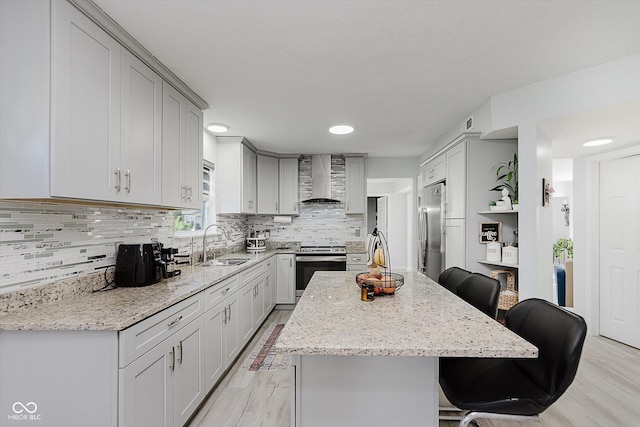 6136 Sandcherry Dr, Indianapolis, IN 46236 - kitchen featuring appliances with stainless steel finishes, wall chimney exhaust hood, light wood-style flooring, a breakfast bar area, and light stone countertops