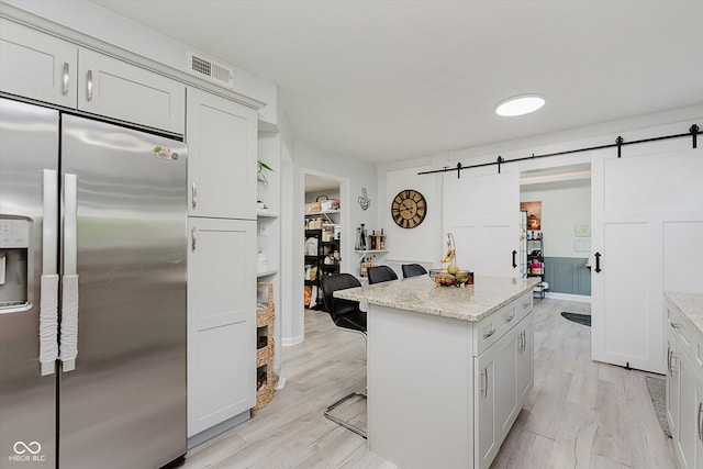 6136 Sandcherry Dr, Indianapolis, IN 46236 - kitchen with stainless steel refrigerator with ice dispenser, a breakfast bar area, a barn door, a center island, and light stone countertops