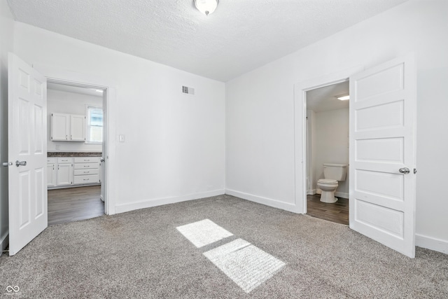 1621 E Kelly St, Indianapolis, IN 46203 - unfurnished bedroom featuring carpet flooring, ensuite bath, and a textured ceiling