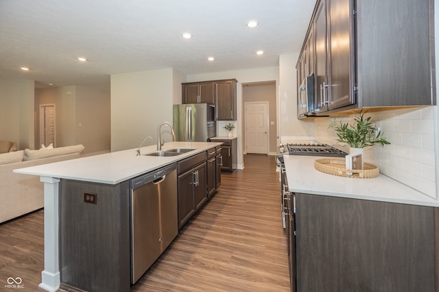 20141 Willenhall Way, Westfield, IN 46074 - kitchen featuring appliances with stainless steel finishes, open floor plan, dark brown cabinets, dark wood-style floors, and a kitchen island with sink