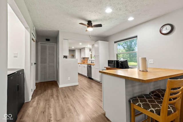 296 Summit Ridge Dr, Greenwood, IN 46142 - kitchen with wood counters, washing machine and dryer, stainless steel dishwasher, light wood finished floors, and a kitchen bar