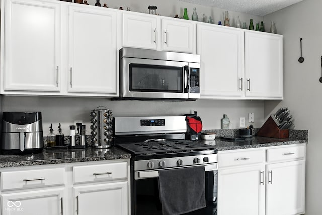 8147 Retreat Ln, Indianapolis, IN 46259 - kitchen with stainless steel appliances, white cabinetry, dark stone counters, and a textured ceiling