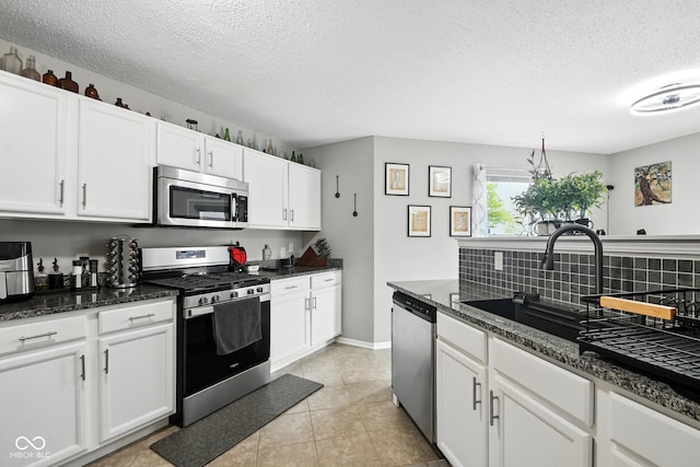 8147 Retreat Ln, Indianapolis, IN 46259 - kitchen with appliances with stainless steel finishes, a textured ceiling, tasteful backsplash, white cabinetry, and light tile patterned flooring