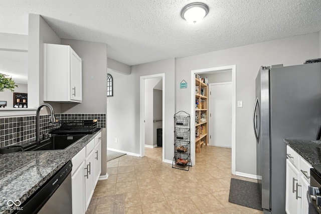 8147 Retreat Ln, Indianapolis, IN 46259 - kitchen with appliances with stainless steel finishes, dark stone counters, white cabinets, tasteful backsplash, and a textured ceiling