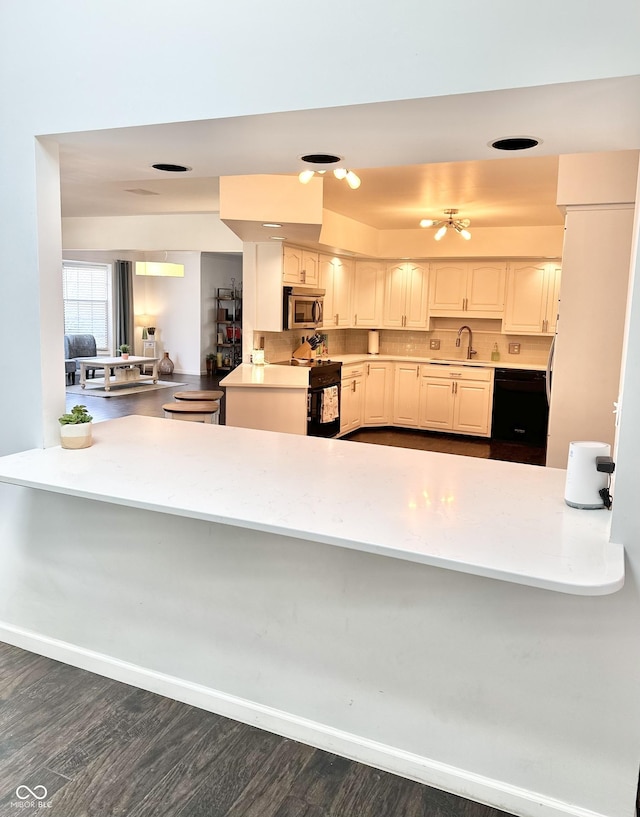 401 Dellwood Dr, Covington, IN 47932 - kitchen featuring stainless steel microwave, black range with electric stovetop, a peninsula, and dark wood-style flooring