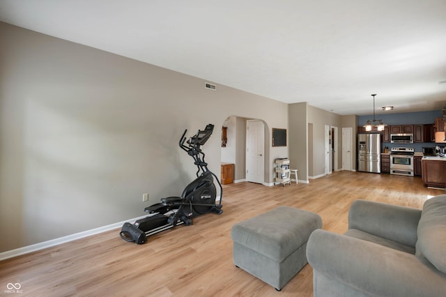8365 Captain Dr, Avon, IN 46123 - living room featuring light wood finished floors, arched walkways, and a chandelier