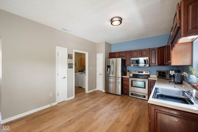 8365 Captain Dr, Avon, IN 46123 - kitchen with appliances with stainless steel finishes, independent washer and dryer, light countertops, and light wood-style floors