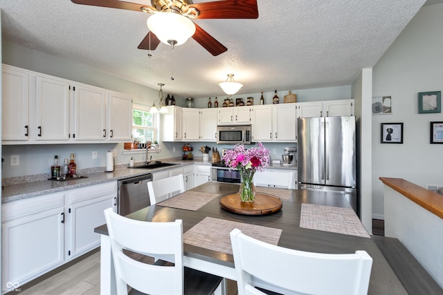 2082 Fiesbeck Dr, Columbus, IN 47201 - kitchen featuring stainless steel appliances, white cabinets, light wood-type flooring, a textured ceiling, and light countertops