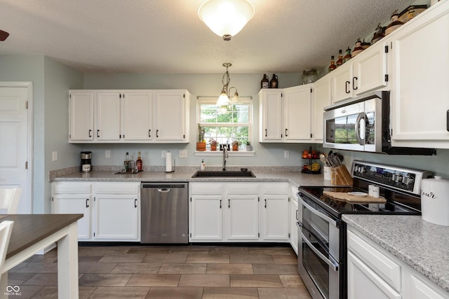 2082 Fiesbeck Dr, Columbus, IN 47201 - kitchen with appliances with stainless steel finishes, white cabinetry, hanging light fixtures, a textured ceiling, and wood finish floors
