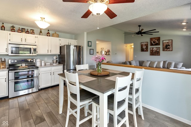 2082 Fiesbeck Dr, Columbus, IN 47201 - kitchen with stainless steel appliances, a ceiling fan, vaulted ceiling, wood finished floors, and white cabinetry