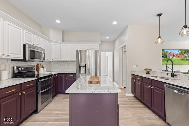 5910 Hickory Woods Dr, Plainfield, IN 46168 - kitchen featuring appliances with stainless steel finishes, light wood-type flooring, a kitchen island, light stone counters, and tasteful backsplash