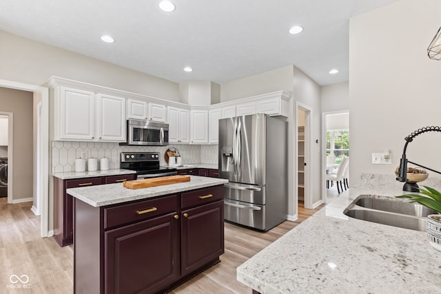 5910 Hickory Woods Dr, Plainfield, IN 46168 - kitchen featuring stainless steel appliances, light wood finished floors, white cabinets, tasteful backsplash, and light stone countertops
