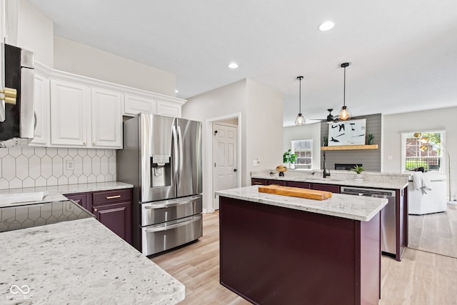 5910 Hickory Woods Dr, Plainfield, IN 46168 - kitchen featuring appliances with stainless steel finishes, a peninsula, a kitchen island, tasteful backsplash, and light wood-style floors