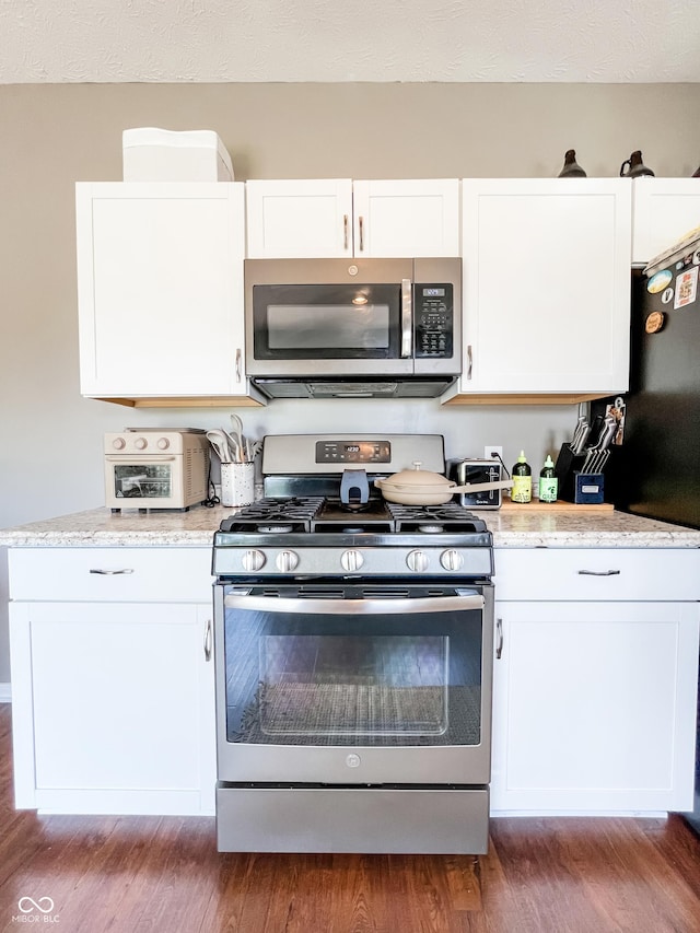 258 Center Ln, Crawfordsville, IN 47933 - kitchen featuring appliances with stainless steel finishes, white cabinets, wood finished floors, and light stone countertops