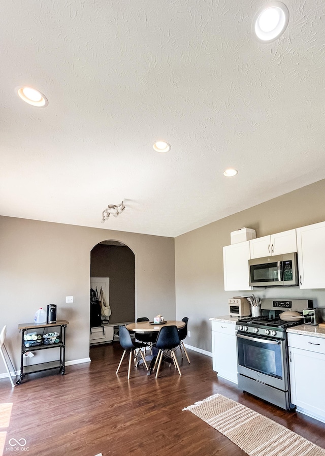 258 Center Ln, Crawfordsville, IN 47933 - kitchen with appliances with stainless steel finishes, arched walkways, white cabinets, dark wood finished floors, and recessed lighting