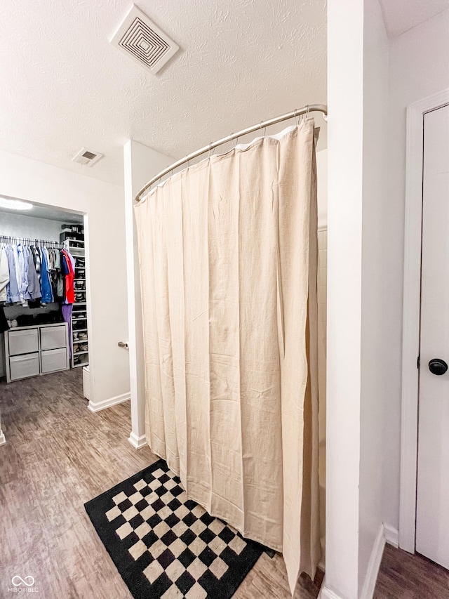 258 Center Ln, Crawfordsville, IN 47933 - full bathroom featuring wood finished floors, a spacious closet, a shower with curtain, and a textured ceiling