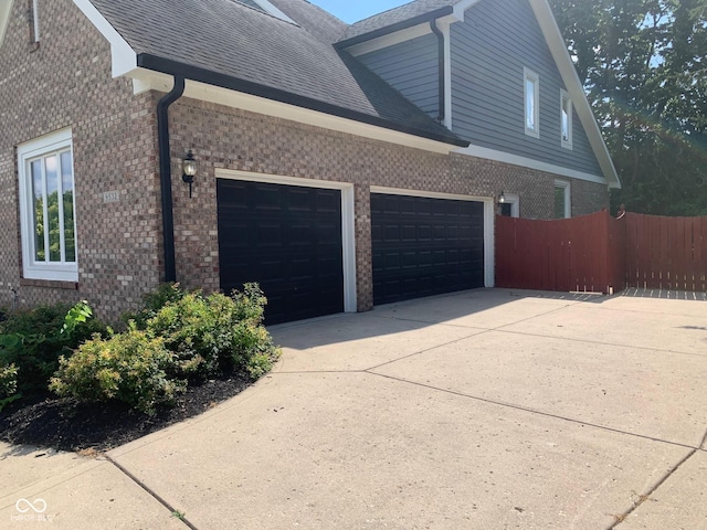 9532 Pinecreek Dr, Indianapolis, IN 46256 - view of side of home with brick siding, a garage, driveway, and roof with shingles