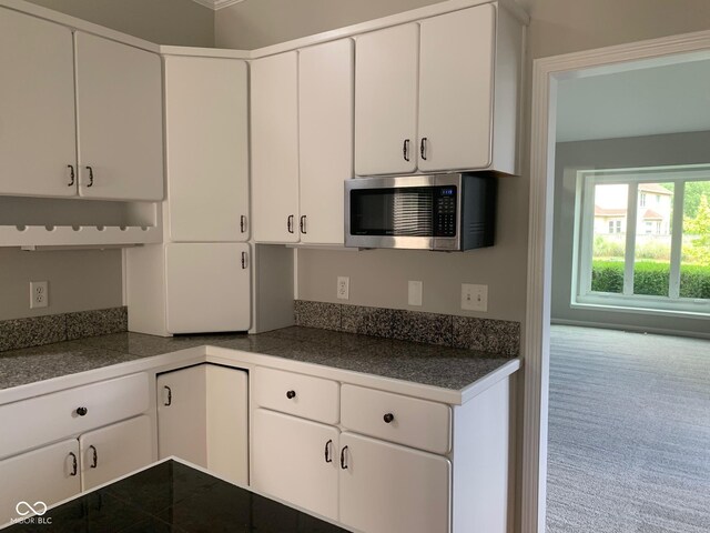 9532 Pinecreek Dr, Indianapolis, IN 46256 - kitchen with stainless steel microwave, tile countertops, white cabinets, and carpet floors