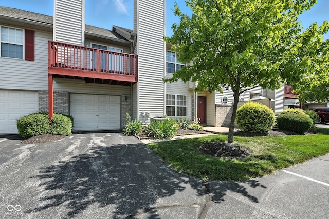 3096 Wildcat Ln, Indianapolis, IN 46203 - view of front facade with a chimney, brick siding, a balcony, an attached garage, and asphalt driveway