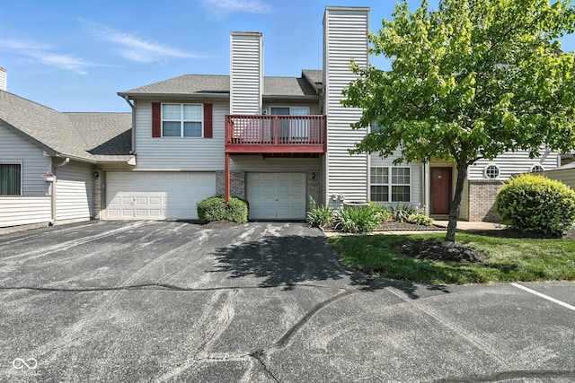 3096 Wildcat Ln, Indianapolis, IN 46203 - view of front of home with a balcony, a garage, asphalt driveway, roof with shingles, and brick siding