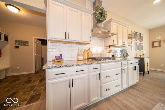 1615 N Blue Rd, Greenfield, IN 46140 - kitchen with backsplash, white cabinetry, light stone countertops, wall chimney range hood, and stainless steel gas stovetop
