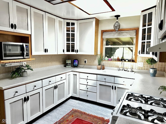 6209 N Parker St, Indianapolis, IN 46220 - kitchen featuring stainless steel microwave, gas range, light countertops, tasteful backsplash, and glass insert cabinets