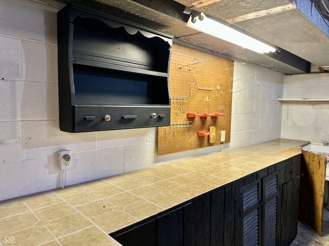 6209 N Parker St, Indianapolis, IN 46220 - kitchen with tile countertops, open shelves, concrete block wall, tile patterned floors, and dark cabinetry