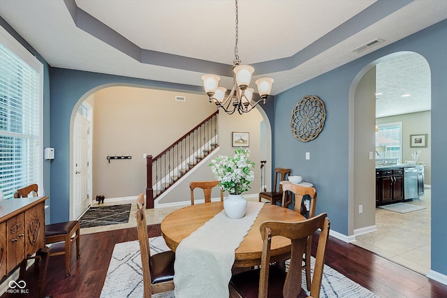 823 Colin Dr, Avon, IN 46123 - dining area with arched walkways, light wood-style floors, stairway, a raised ceiling, and a chandelier