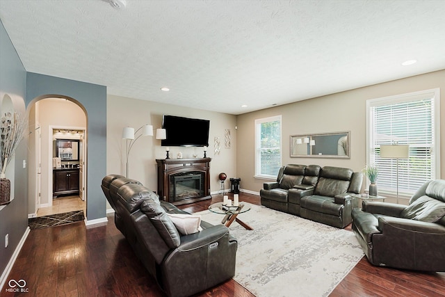 823 Colin Dr, Avon, IN 46123 - living area with arched walkways, dark wood-style flooring, a textured ceiling, a glass covered fireplace, and recessed lighting
