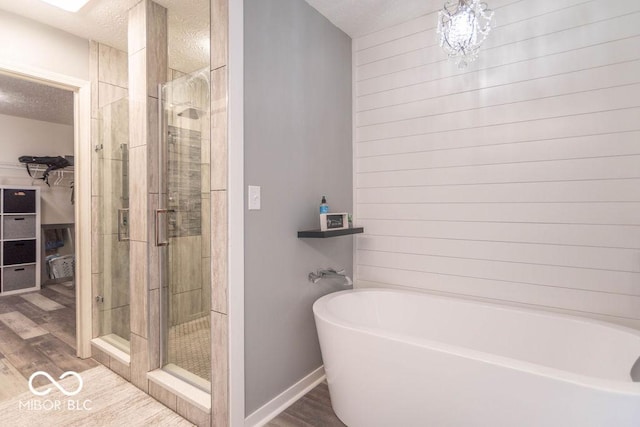 10450 Wintergreen Way, Indianapolis, IN 46234 - bathroom featuring a soaking tub, wood finished floors, a spacious closet, a stall shower, and a textured ceiling