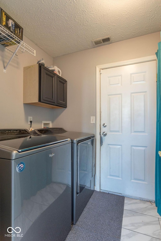 10450 Wintergreen Way, Indianapolis, IN 46234 - washroom with independent washer and dryer, cabinet space, a textured ceiling, and light marble finish flooring