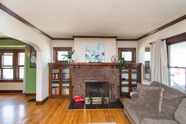 3459 W Michigan St, Indianapolis, IN 46222 - living area featuring a brick fireplace, wood finished floors, arched walkways, plenty of natural light, and ornamental molding