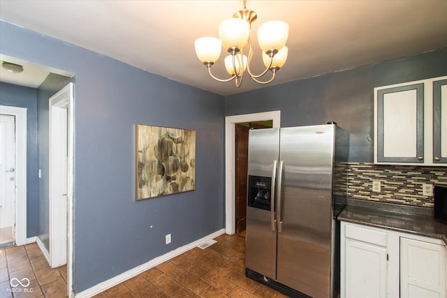 3459 W Michigan St, Indianapolis, IN 46222 - kitchen featuring stainless steel fridge with ice dispenser, dark countertops, tasteful backsplash, white cabinetry, and a chandelier