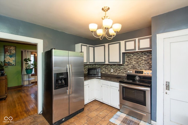 3459 W Michigan St, Indianapolis, IN 46222 - kitchen featuring stainless steel appliances, dark countertops, backsplash, a chandelier, and white cabinetry