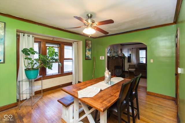 3459 W Michigan St, Indianapolis, IN 46222 - dining area with arched walkways, a ceiling fan, wood-type flooring, crown molding, and a brick fireplace