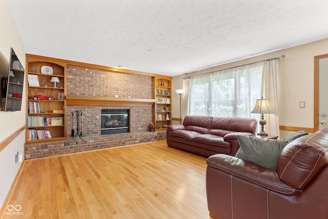 7621 Forest Dr, Fishers, IN 46038 - living area with wood finished floors, a textured ceiling, a fireplace, brick wall, and built in shelves