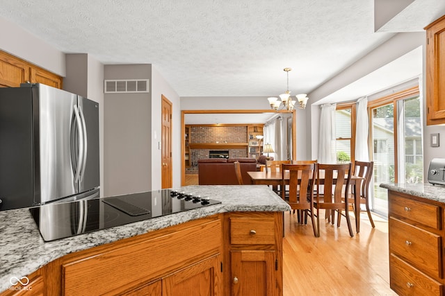 7621 Forest Dr, Fishers, IN 46038 - kitchen featuring freestanding refrigerator, black electric cooktop, light wood-style flooring, open floor plan, and pendant lighting