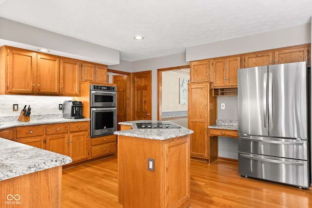 7621 Forest Dr, Fishers, IN 46038 - kitchen with appliances with stainless steel finishes, light wood-type flooring, a center island, brown cabinetry, and recessed lighting