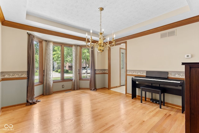 7621 Forest Dr, Fishers, IN 46038 - dining space with a chandelier, a raised ceiling, light wood-style flooring, and a textured ceiling