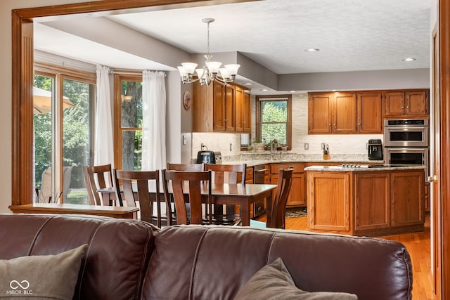 7621 Forest Dr, Fishers, IN 46038 - kitchen featuring plenty of natural light, light wood finished floors, open floor plan, brown cabinets, and a textured ceiling