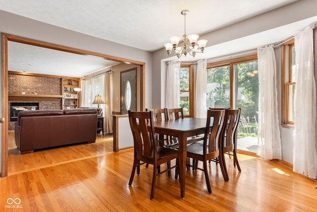7621 Forest Dr, Fishers, IN 46038 - dining area featuring a chandelier, light wood finished floors, and a fireplace