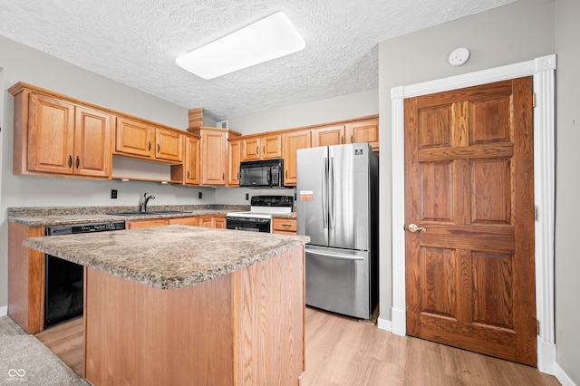 115 Jordan Rd, Indianapolis, IN 46217 - kitchen with black appliances, light wood-type flooring, a kitchen island, a textured ceiling, and light countertops